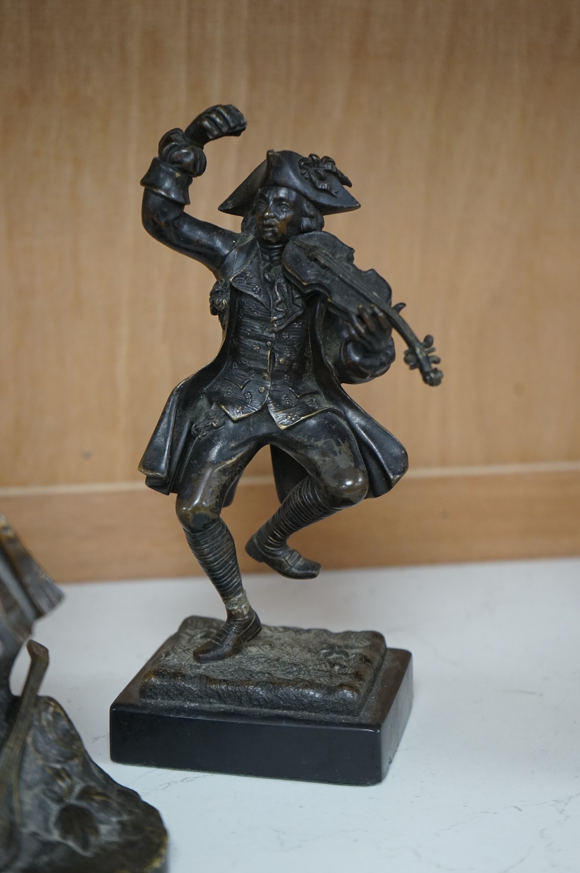 A small bronze figure of a male violinist and another bronze female figure with a lute against a rock, tallest 23cm high
